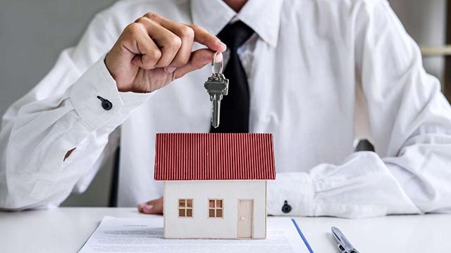 person-holding-keys-over-a-house-figurine